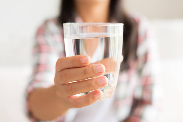 幸せな美しい若い女性は彼女の手で水を飲むガラスを保持しています。医療コンセプト。 - drink glass ストックフォトと画像