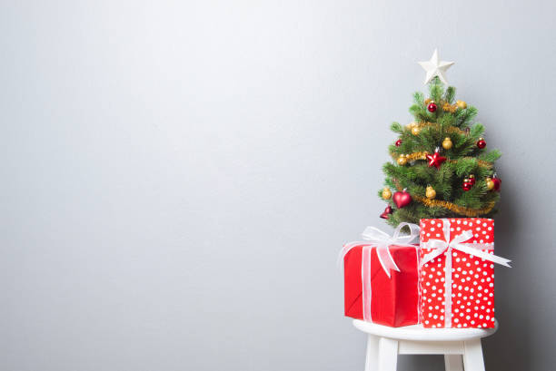 istock Gift boxes and small decorated Christmas tree on gray wall 1042128702