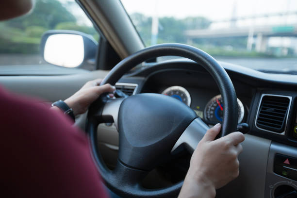 istock Hands holding steering wheel while driving car on city road 1042128746