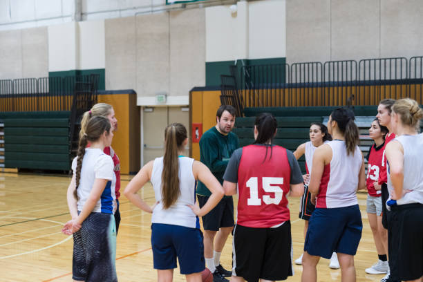 istock Coach pulls his college women's basketball team together for a huddle 1042146578