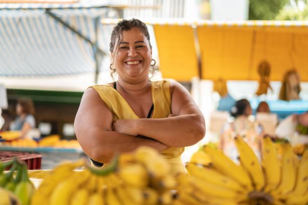 portret van vertrouwen eigenaar - verkoop van bananen op de boerenmarkt - straatverkoper stockfoto's en -beelden