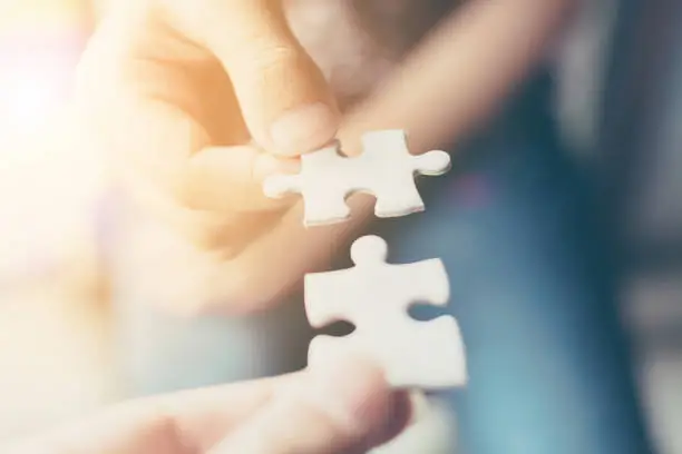 Photo of Hand of two people holding jigsaw puzzle connecting together. Concept of partnership and teamwork in business strategy