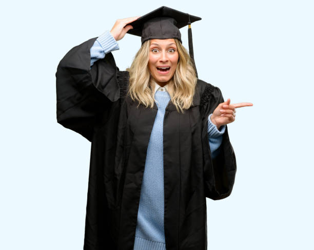 istock Young graduate woman pointing away side with finger 1042161032