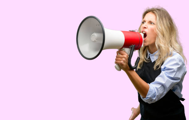 istock Young shop owner wearing black apron communicates shouting loud holding a megaphone, expressing success and positive concept, idea for marketing or sales 1042161366