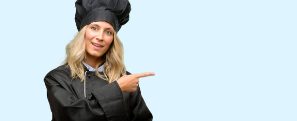 istock Beautiful cook woman chef pointing away side with finger 1042161378