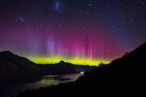 Spectacular view as aurora lights up the sky of Queenstown, New Zealand. When particles from a solar storm reached our Earth, it creates an array of colored lights as they hit the atmosphere.