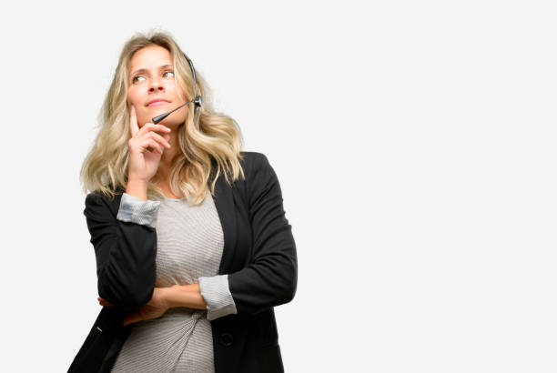 Young woman operator from call center thinking and looking up expressing doubt and wonder