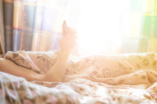 istock person use smartphone in the morning while lying in bed at home under blanket v 1042164586