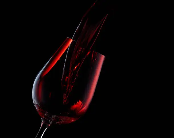 Pouring red wine into a glass on a black background