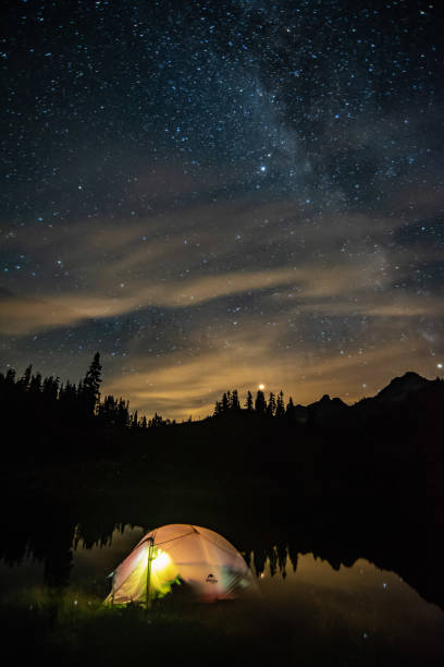istock Moonlit nightsky with lake, forest, mountain and tent. 1042192758