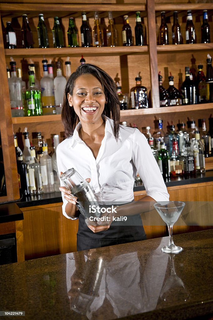 Felice afro-americana donna di miscelazione di cocktail barman dietro il bancone - Foto stock royalty-free di Barman