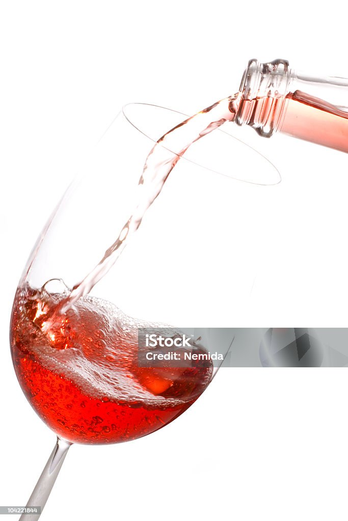 Une bouteille de vin rosé verser dans un verre sur fond blanc. - Photo de Vin rosé libre de droits