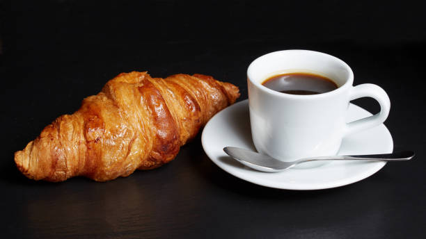 istock Cup of coffee with a croissant on a dark background. 1042232618