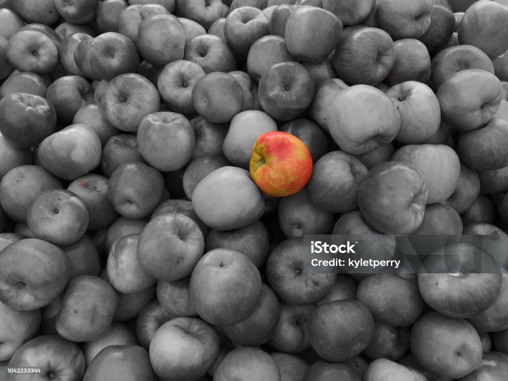 Standing out from the crowd An apple in color stands out against the crowd Black And White Stock Photo