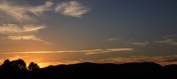 istock Sunset over hills silhouette, scattered clouds on the sky. The sundown is on the left side. 1042236442