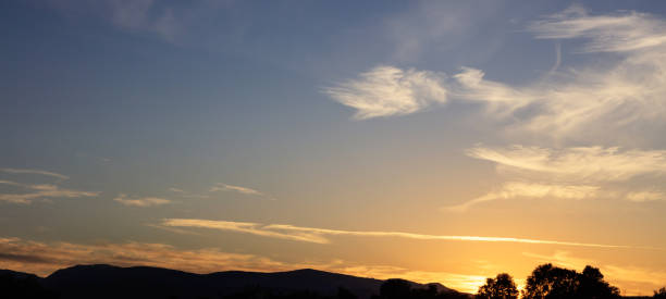istock Sunset over hills silhouette, scattered clouds on the sky. The sundown is on the right side. 1042236464