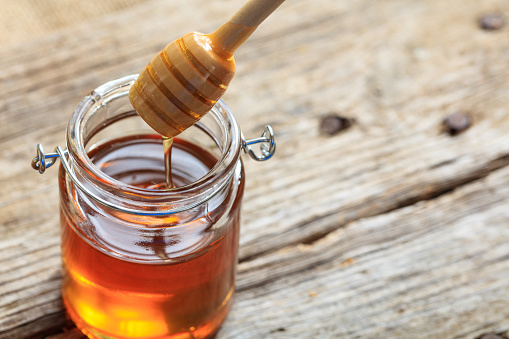 A glass jar with honey on a table