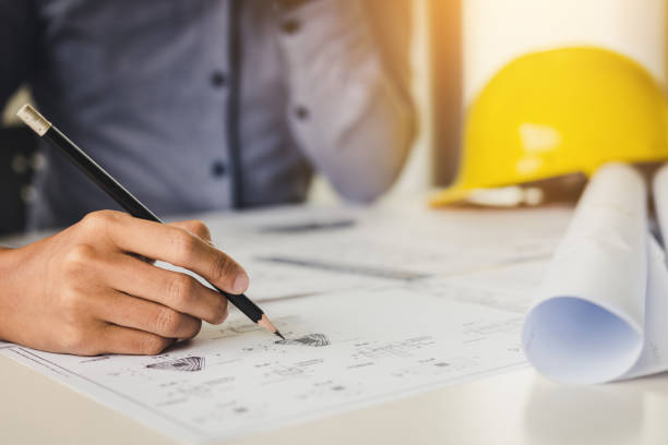istock Architect holding pencil and pointing on blueprint. 1042239870