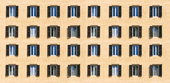 Orange colored façade and windows with shutters, residential building in Montagnola Park complex, Bologna, Italy