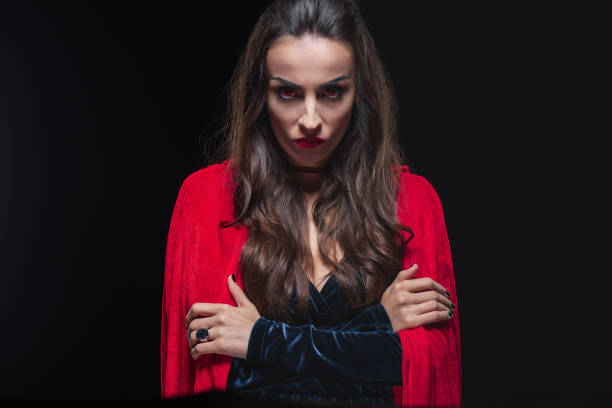 istock grim vampire woman in red cloak looking at camera isolated on black 1042260330