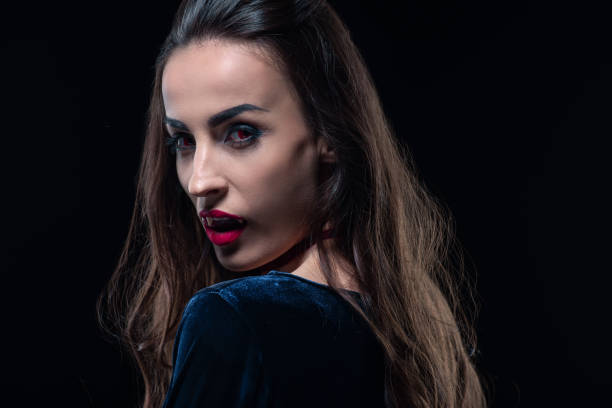istock vampire with red lips looking at camera isolated on black 1042260382