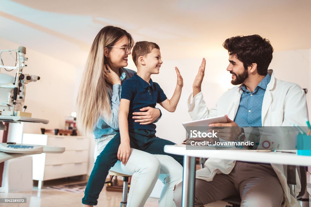 Mother with son choosing glasses in optics store. Doctor Stock Photo