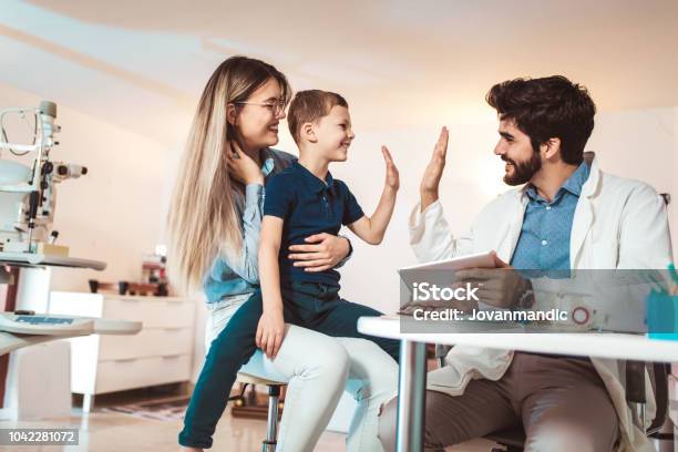Mother With Son Choosing Glasses In Optics Store Stock Photo - Download Image Now - Doctor, Child, Family