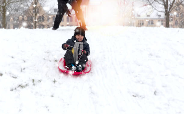 istock Father and son playing with a sled in the snow .Outdoors during snowfall. Active outdoors leisure with children in winter. 1042292356