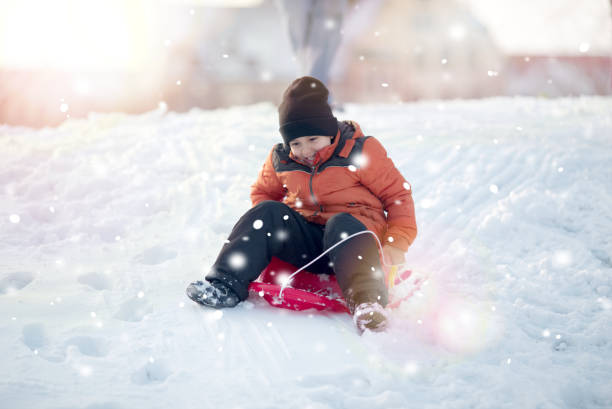 Cute little funny boy having fun on snow, outdoors during snowfall.