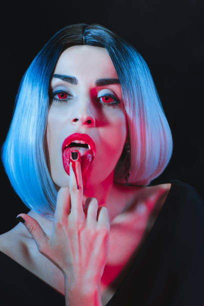 istock sexy vampire licking her middle finger isolated on black 1042294116