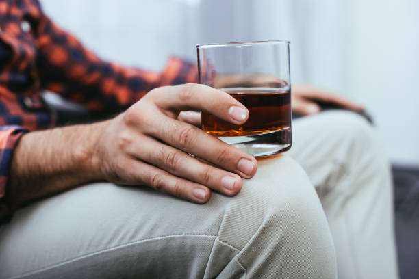 ウィスキーのガラスを保持している若い男のショットをトリミング - alcoholism drunk addiction drinking ストックフォトと画像