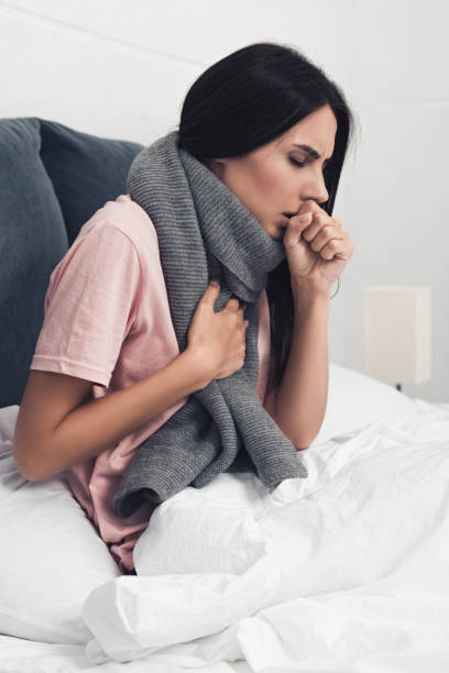 istock sick young woman sitting in bed and having cough 1042298236