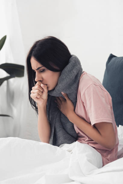 istock sick young woman sitting in bed and having cough 1042298246