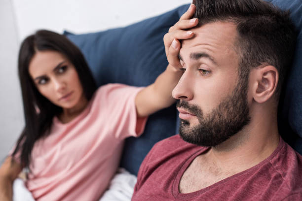 istock young woman touching forehead of sick husband while sitting in bed 1042305114