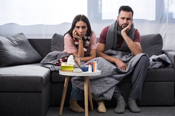 istock diseased young couple with meds on table sitting together on couch 1042305436