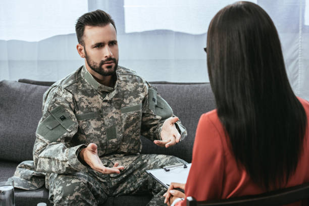 istock sad soldier with ptsd talking at psychiatrist and gesturing while sitting on couch during therapy session 1042305444