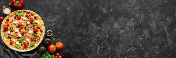 Photo of Italian pizza and pizza cooking ingredients on black concrete background