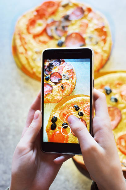 スマート フォンは、新鮮な自家製ピザの写真を撮る - cheese making ストックフォトと画像