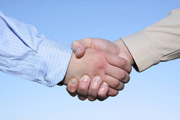 Two hands handshake isolated on sky background stock photo
