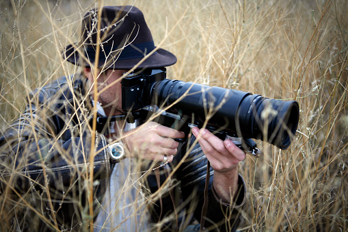 Photographer in tall grass capturing wildlife photos. Camera is a vintage 60s Russian Zenit Photo Sniper.