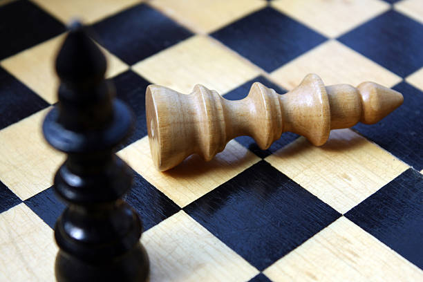 istock Black bishop standing and beige bishop down on a chessboard 104236326
