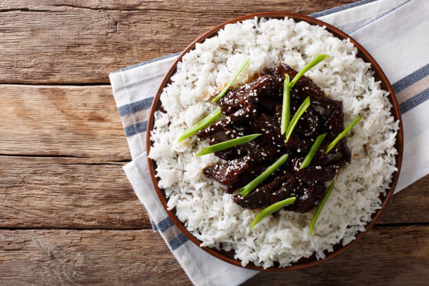Mongolian beef with sauce and garnish of rice. Horizontal top view