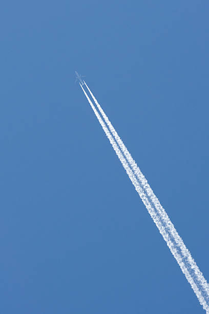 Airplane in a Blue Sky with Vapor Trail stock photo