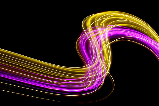Long exposure photography with fairy lights, abstract motion pattern of pink purple and yellow gold against a black background