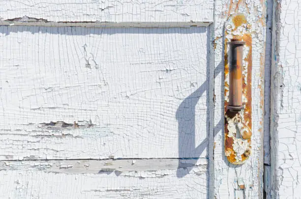 Old wooden door with door knob and cracked paint.