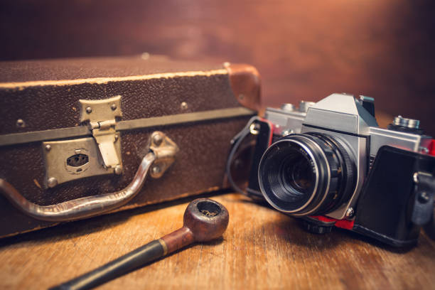 istock Vintage photo camera, smoking pipe and suitcase on table. 1042385458