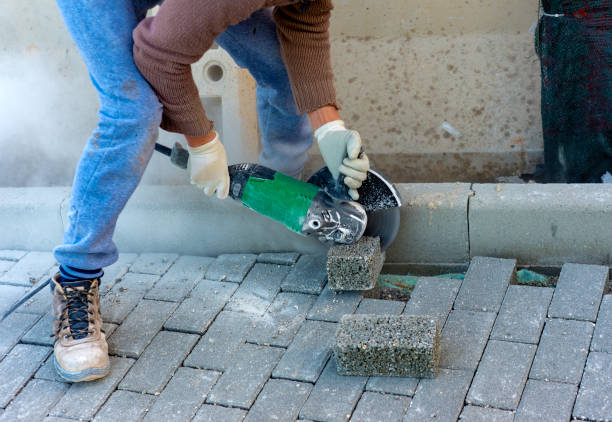 worker cuts a tile to size with an electric grinder to complete the self-locking paving - driveway brick paving stone interlocked imagens e fotografias de stock