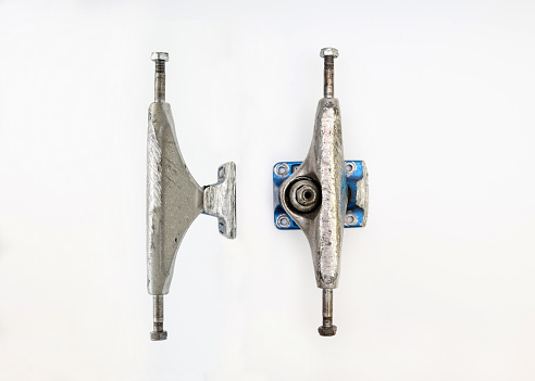 Used silver skateboard parts on a white background, two metal truck from different perspective top and eye level. Skateboard truck sits on a White background