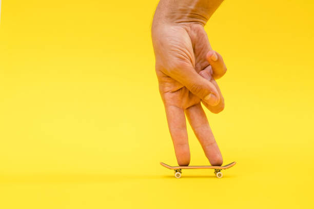 fingerboard. a small skateboard for kids and teenagers to play with hand fingers. isolated on yellow background with space for type - roller skate imagens e fotografias de stock