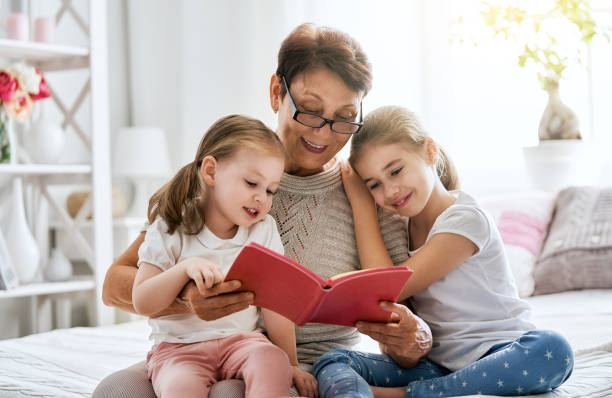 großmutter, einem buch, enkelinnen - grandparent family reading inside of stock-fotos und bilder